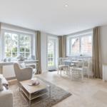 Living and dining area with windows, sofa, armchair, and TV.
