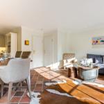 Wohn- und Essbereich mit Terrakottaboden, Sofa, Esstisch und Wandbild.