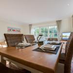 Esszimmer mit Holztisch, geflochtenen Stühlen und Blick auf den Garten.