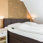 Schlafzimmer mit Bett, Nachttisch und Lampen an der Wand