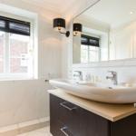 Badezimmer mit Waschbecken, Spiegel und Fenster.