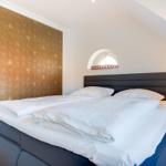 Schlafzimmer mit Doppelbett, goldener Wand und kleinem Fenster