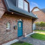 Rotes Backsteinhaus mit blauer Tür und gepflastertem Hof