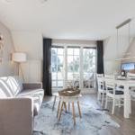 Living and dining area with sofa, table, and windows to the terrace.