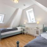 Two bedrooms with sloped ceilings, wooden floors, and windows.