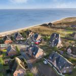 Village with houses by the coast, view of the sea and beach.