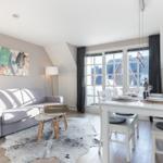 Living and dining area with sofa, dining table, and windows for views.