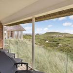Terrasse mit Liegen und Blick auf Dünen und Strand.