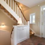 Eingang mit Treppe, weißer Schrank und Terrakottboden.