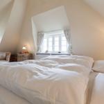 Schlafzimmer mit Doppelbett, Fenster und Sessel.