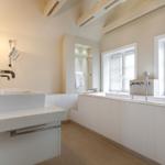 Badezimmer mit Badewanne, Waschbecken und Fenstern.