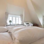 Schlafzimmer mit Dachschrägen, Fenster, Schreibtisch und Globus.