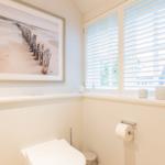 Badezimmer mit Toilette, Fenster und Wandbild.