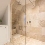 Duschkabine mit Glaswand, Steinfliesen und Handbrause