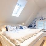 Schlafzimmer mit Dachschrägen, Dachfenster und Fenster mit Jalousie.