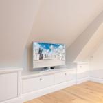 Dachgeschosszimmer mit TV und weißen Schränken.