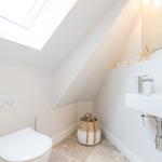 Duschbad mit Dachfenster, Waschbecken und Toilette. Holzkorb und Seestern dekorieren den Raum.