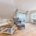 Wohn- und Essbereich mit Sofa, Sessel und Holzboden.