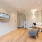 Wohnzimmer mit Sofa, Sitzhocker und Fernseher in Wandnische.