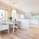 Essbereich mit Tisch, Stühlen und Fenstern. Küche mit Arbeitsplatte und TV.