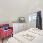 Bedroom with bed, TV, and red armchair.