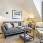 Living room with sofa, armchair, and coffee table under sloped ceiling.