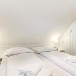 Room with two beds, white walls, and nightstands with lamps.