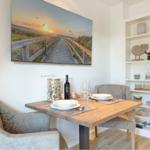 Dining table with two chairs, wall picture, and shelf with decorative items.