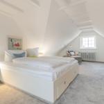 Schlafzimmer mit Dachschrägen, Bett, Nachttisch und Fernseher