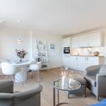 Wohnküche mit Esstisch, zwei Sesseln und einer Glasplatte.