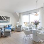 Wohn- und Essbereich mit Tisch, Stühlen und Sofa. Große Fensterfront mit Blick.