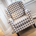 Sofa mit kariertem Stoff und dunklen Beinen auf Holzboden.