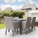 Terrasse mit Esstisch und Stühlen, Strandkorb und Garten.
