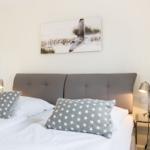 Schlafzimmer mit Bett, Kopfkissen und Wandbild.