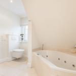 Bad mit Whirlpool, Toilette und Fenster mit Rollladen.
