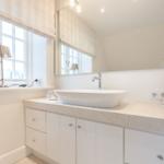 Badezimmer mit Waschbecken, Spiegel und Fenster