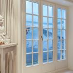 Durch die Fenster sieht man das Meer mit Wellen. Eine Buddha-Statue steht auf einem Tisch.