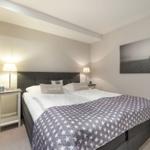 Schlafzimmer mit Doppelbett, Nachttischen und Wandbild.