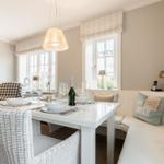 Esszimmer mit weißem Tisch, weißen Stühlen und Fenstern mit Raffstoren.