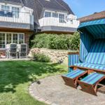 Hinterhof mit Strandkorb, Grasfläche und Terrasse vor einem Haus.