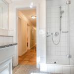Badezimmer mit Dusche, Waschtisch und Heizung.