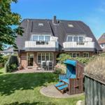 Haus mit Garten, Terrasse und Strandkorb. Zwei Balkone und großer Rasenbereich.