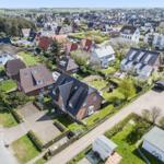 Luftbild eines Wohngebiets mit Häusern, Grünflächen und Straßen.