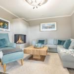 Wohnzimmer mit Sofa, Sessel, Kamin und Holztisch.