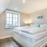 Schlafzimmer mit Doppelbett, Fenster und Nachttischen.