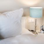 Bettkopfteil mit Kissen, Nachttisch mit Lampe und Figur