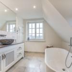 Badezimmer mit freistehender Badewanne, Waschtisch und Fenster