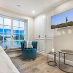 Zimmer mit Blick aufs Meer, blauer Sessel, TV und Kleiderschrank.