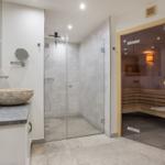 Badezimmer mit Dusche, Sauna und Steinwaschbecken.