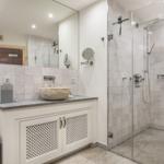 Badezimmer mit Dusche, Waschbecken und Spiegel